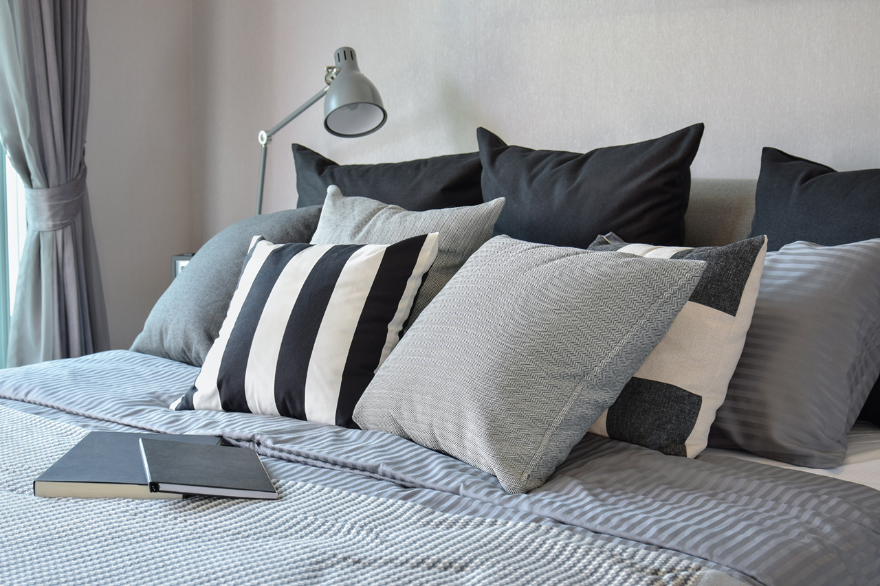 stylish bedroom interior design with black patterned pillows on bed and decorative table lamp.