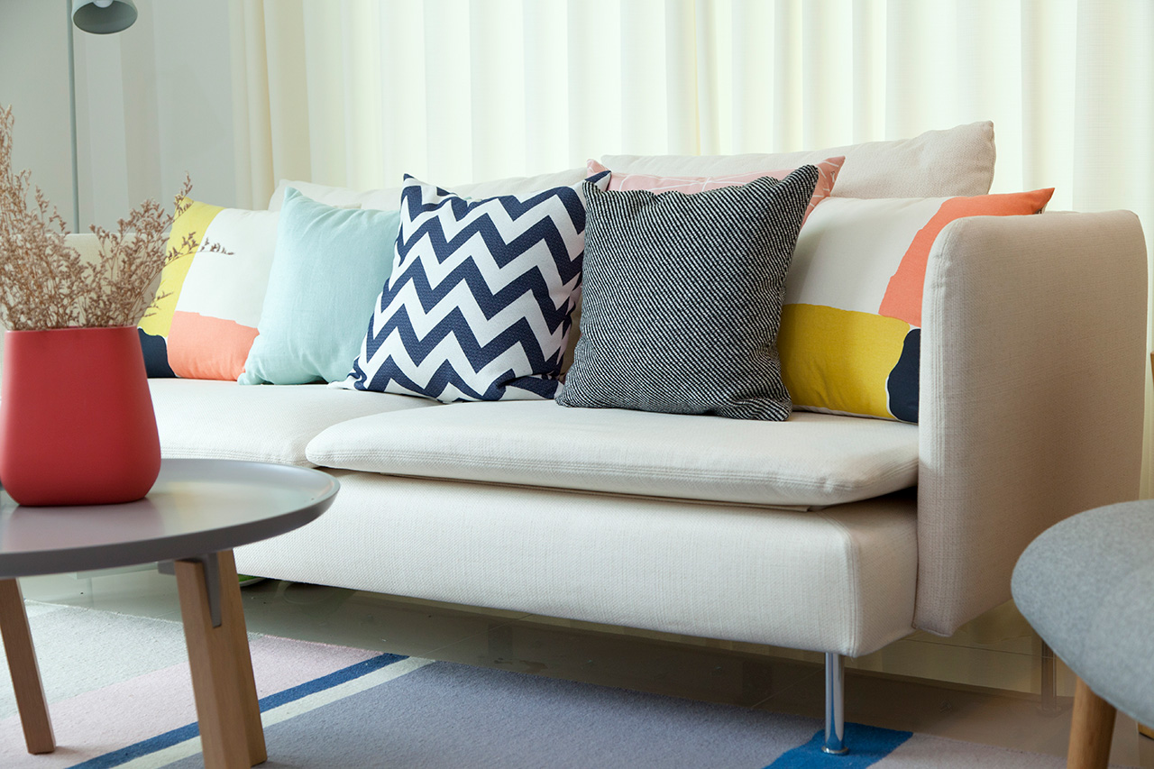 Stylish red vase on table in living room in front of sofa